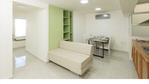 A compact living space with a sofa, dining table, and a green shelving unit. - Room-appartment Rodolfo Historical Centr (Mazatlán)