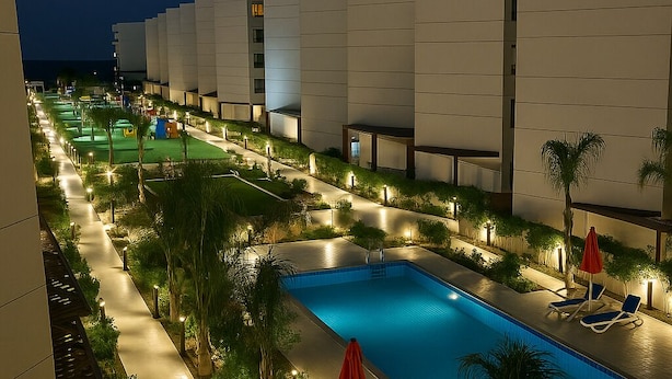 A nighttime view of a hotel pool area with a swimming pool, lounge chairs, and palm trees. - Luxurious Chalet With Sea Views in Port Said, Egypt (Al-Manasrah)