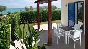 A covered patio with a table and chairs, overlooking a beach. - Dolce Mare 1 - Ground Floor With Garden (Modica)