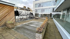 Enjoy the rooftop view from a comfortable bench amidst lush greenery and bicycles.