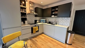 Compact kitchen with oven, stovetop, and sink, complete with a range hood and modern appliances.
