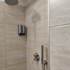 A shower area with a handheld showerhead and a wall-mounted body spray.