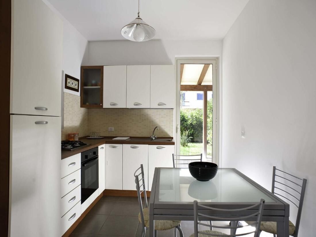 A modern kitchen with white cabinets, a black oven, and a dining table with chairs.