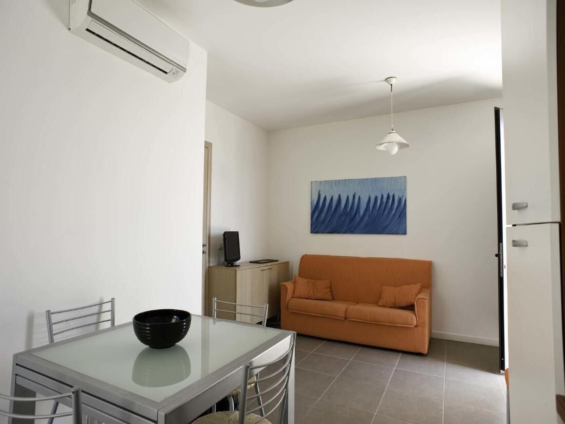 A compact living space with a dining table, a sofa, and a painting on the wall.