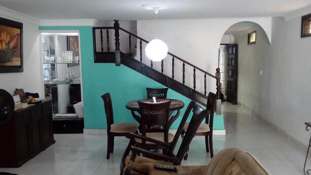 A living room with a staircase, a dining area, and a kitchen visible through an open door. - Room in House - Taminaka Hostel en Santa Marta - Shared Room 1 (Santa Marta)