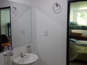 A bathroom with a sink, mirror, and two towel rings on the wall.