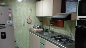 A compact kitchen with a gas stove, sink, and a refrigerator. - Room in House - Taminaka Hostel en Santa Marta - Shared Room 1 (Santa Marta)