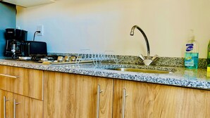 A kitchen with wooden cabinets, a stainless steel sink, a coffee maker, and a dish rack. - Mayakoba Cozy 2-bedroom Apartment With Amenities (Playa del Carmen)
