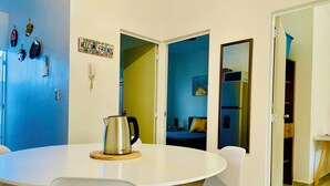 A modern dining area with a round table, white chairs, and a stainless steel kettle. - Mayakoba Cozy 2-bedroom Apartment With Amenities (Playa del Carmen)