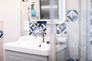 Une salle de bain avec un lavabo blanc, un miroir et des carreaux à motifs.