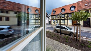 Straßenansicht mit traditionellen Fachwerkhäusern, einer Kopfsteinpflasterstraße und parkenden Autos.