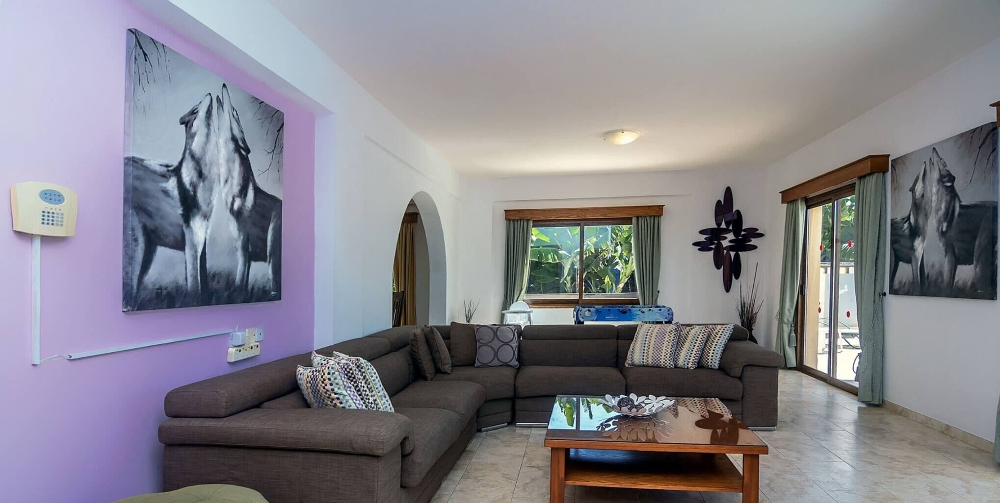 A living room with a sectional sofa, a coffee table, and artwork on the walls.