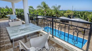 Ein Balkon mit Pool, weißen Stühlen und einem Tisch.