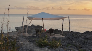 Une plage avec un auvent et deux chaises en bois donnant sur la mer.