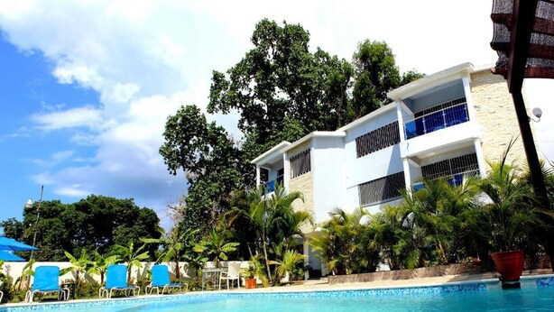 A pool area with lounge chairs and a two-story building with balconies. - Cozy And Comfort 2br-2bt Apartment In Centralsosua (Sosúa)