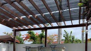 An outdoor patio area with a pool, stone flooring, and three black bar stools against a stone wall. - Cozy And Comfort 2br-2bt Apartment In Centralsosua (Sosúa)