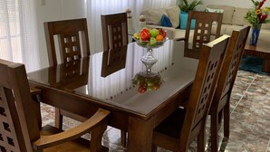 A dining area with a wooden table and chairs, a fruit bowl, and a clock on the wall. - Cozy And Comfort 2br-2bt Apartment In Centralsosua (Sosúa)