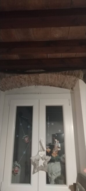 Una habitación con techo de madera y puerta blanca con paneles de vidrio esmerilado.