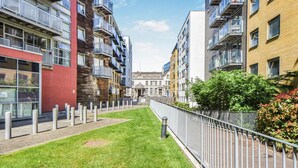 Un moderno complejo de apartamentos urbanos con varios balcones, un patio central y una mezcla de estilos arquitectónicos.
