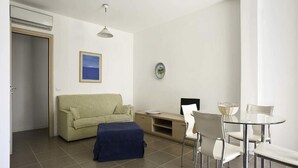 A modern living room with a sofa, a glass dining table, and a coffee table. - Dolce Mare 4 - Sea Front - Large Balcony - Sandy Beach (Modica)