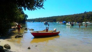 Un bote en aguas tranquilas con una orilla boscosa y otros botes al fondo.