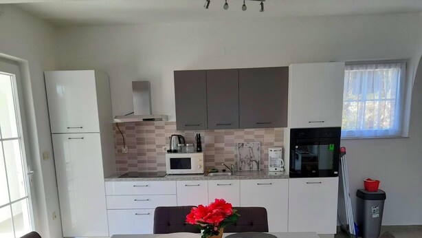 Una cocina moderna con armarios blancos, un microondas y una cafetera.