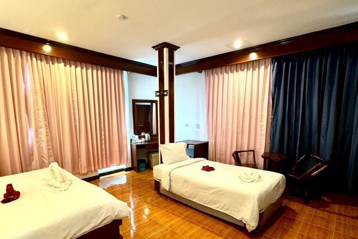 Habitación de hotel con dos camas, piso de madera y cortinas.
