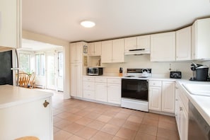 A kitchen with white cabinets, a microwave, stove, and a coffee maker.