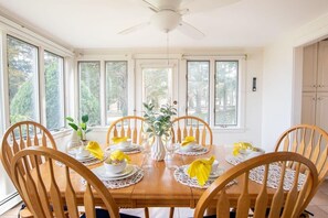 A dining area with a wooden table set for six, surrounded by six wooden chairs.