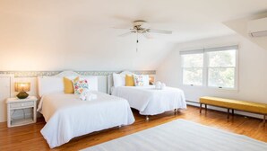 Ein Schlafzimmer mit zwei Betten, einem Deckenventilator, einer Bank und einem Fenster.