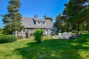 A two-story house with a covered patio area, a fenced yard, and a well-maintained lawn.