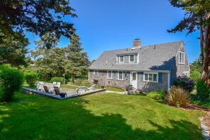 A two-story house with a well-maintained lawn and patio furniture.