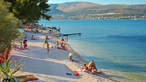 Una spiaggia con persone che prendono il sole e nuotano.
