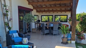 Une terrasse extérieure aménagée avec des meubles en osier, une pergola et des plantes en pot.