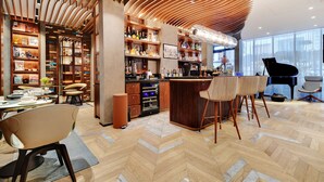 A modern bar area with wooden shelves, a piano, and a seating arrangement. - CARD Hôtel (Paris)