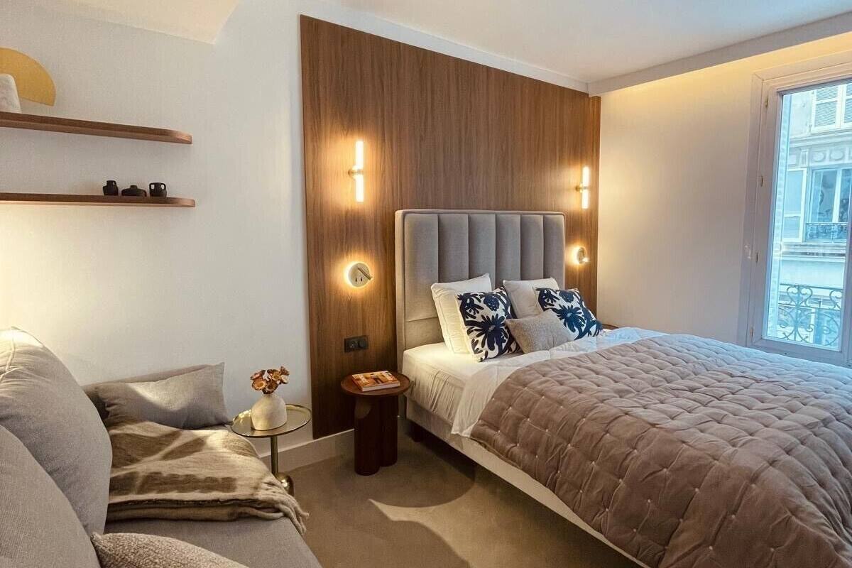 A modern bedroom with a large bed, a sofa, and a small side table.
