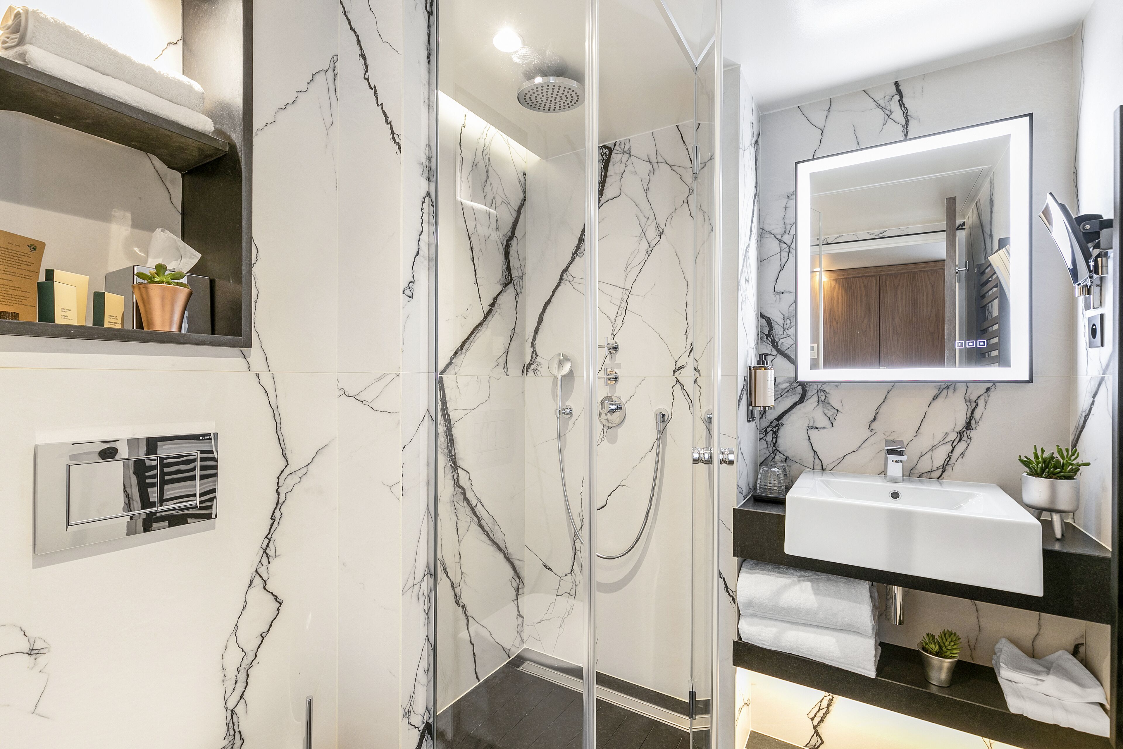 A modern bathroom with a glass-enclosed shower, a white sink, and a marble backsplash.