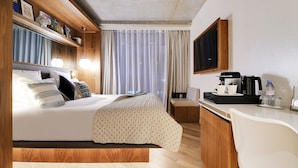 A hotel room with a bed, bedside table, TV, and a desk with a chair. - CARD Hôtel (Paris)