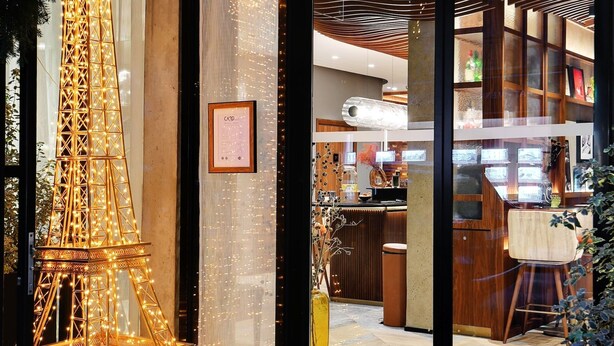 A hotel entrance with a large illuminated Eiffel Tower model, a reception desk, and a modern interior visible through the glass doors. - CARD Hôtel (Paris)
