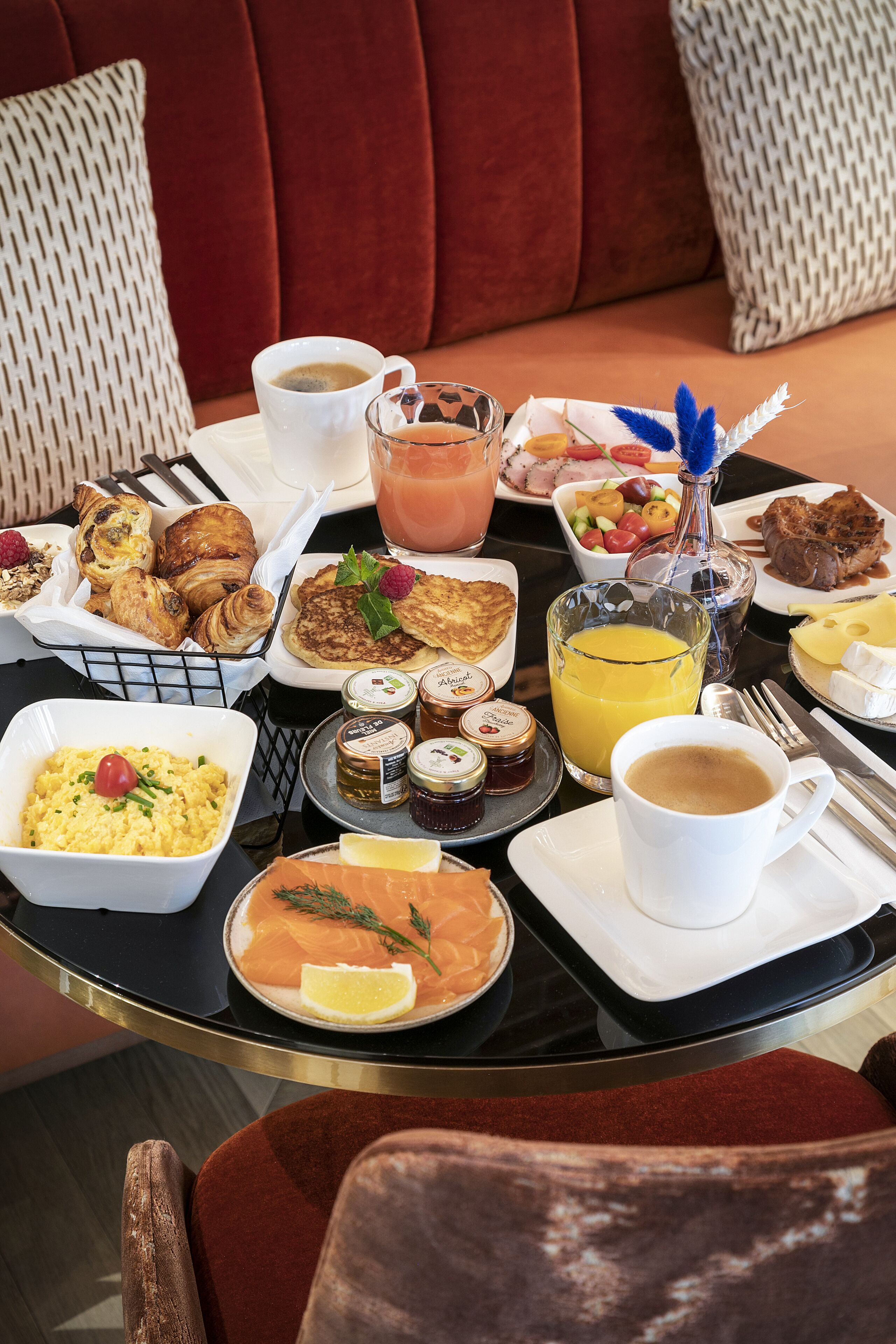 Un bufé de desayuno con diversos platos, incluyendo pasteles, frutas y bebidas, sobre una mesa redonda.