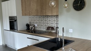 A modern kitchen with a central island, stainless steel appliances, and a patterned backsplash.