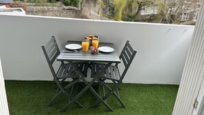 A balcony with a table set for breakfast, including croissants, juice, and berries.