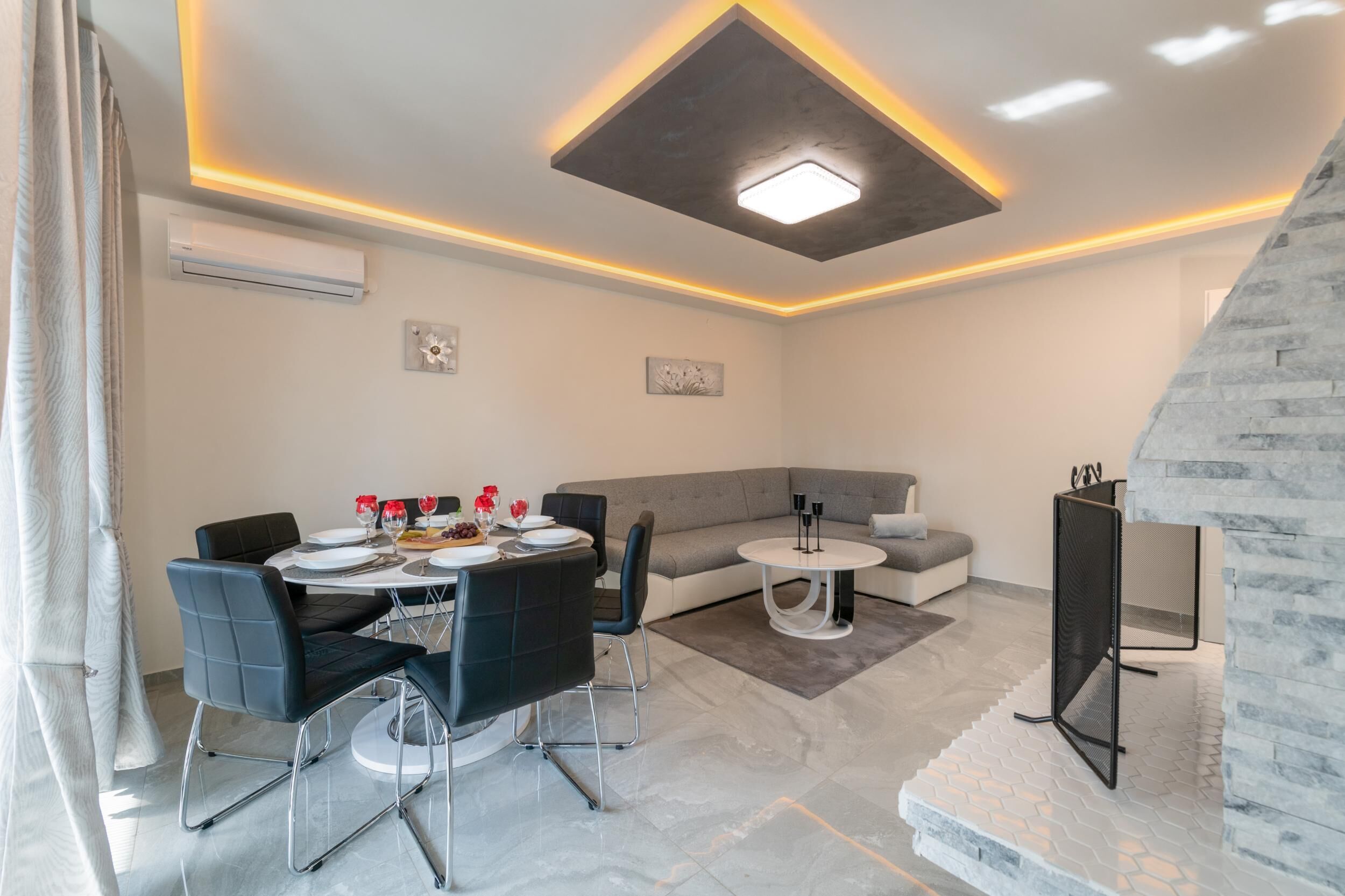 Un salon moderne avec un coin repas, comprenant un canapé, une table à manger avec des chaises, une petite table ronde et un meuble pour la télévision.
