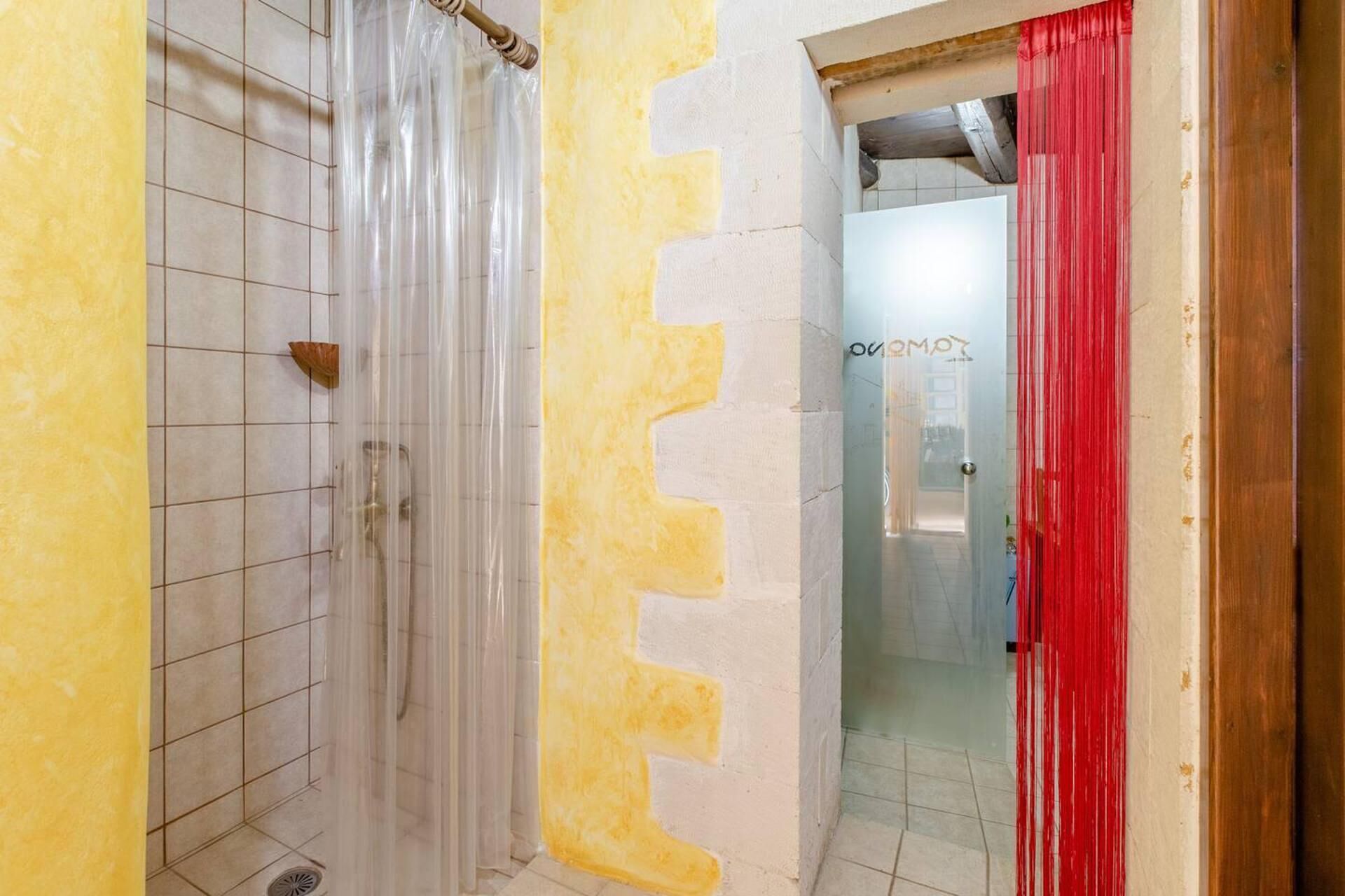 A bathroom with a shower, tiled walls, and a partially painted wall.