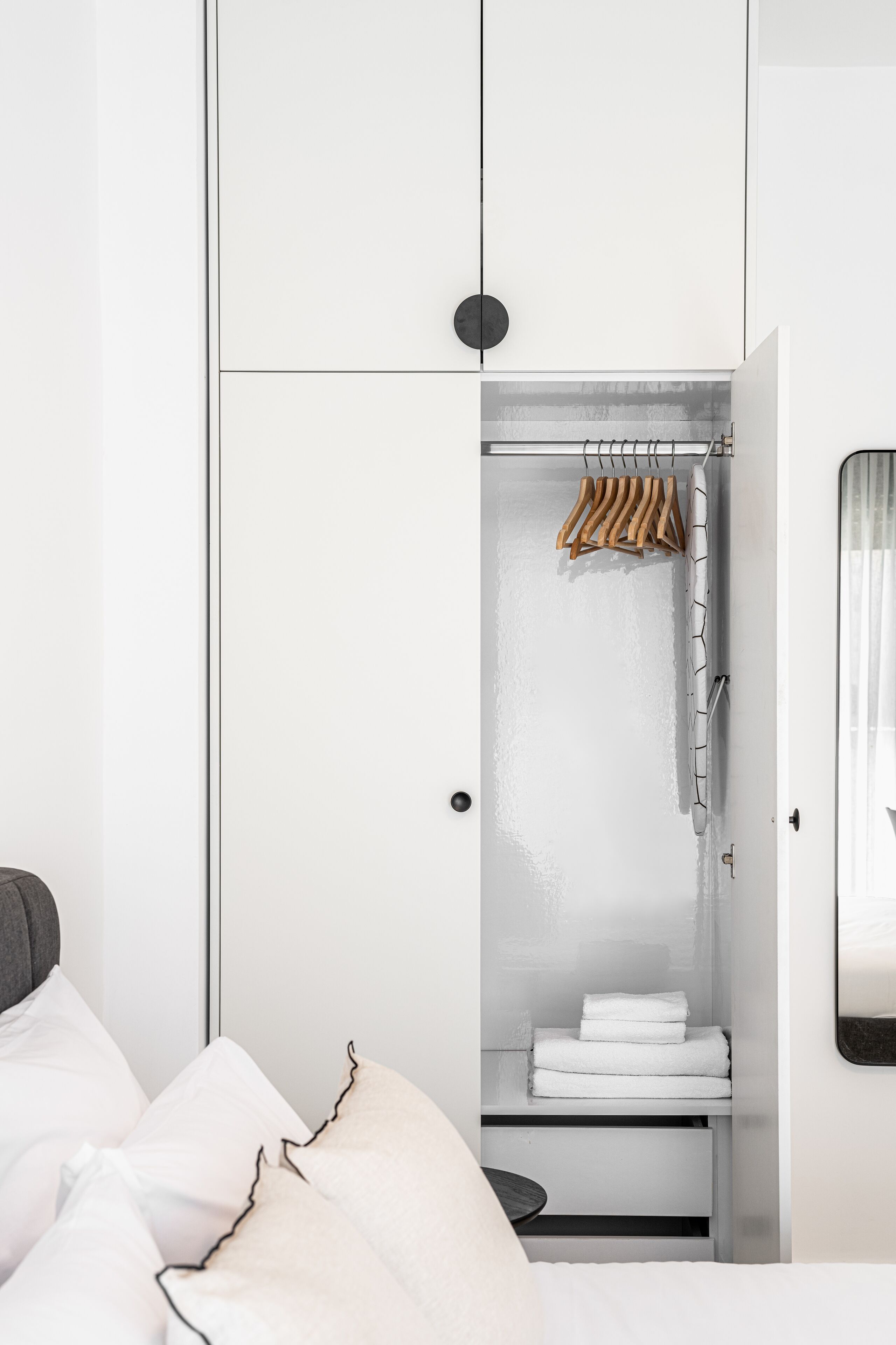 A white wardrobe with a hanging rack and a shelf with folded towels.