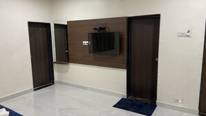 A hallway with two doors, a wall-mounted television, and a blue mat at the entrance. - Hotel Millennium Plaza (Jamnagar)