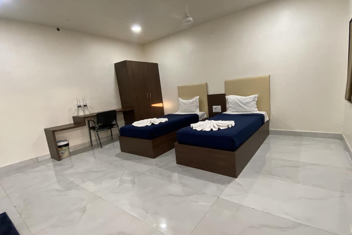 A hotel room with two beds, a desk, and a wardrobe.