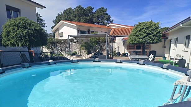 Una piscina con un’amaca, lettini e un cielo azzurro terso.