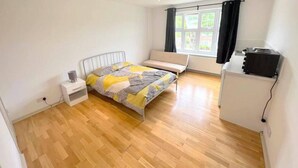 A bedroom with a bed, a bench, a desk, and a projector.