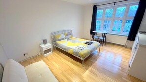 A bedroom with a bed, bedside table, and a window with curtains.